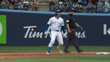 a baseball player wearing a blue jays jersey runs towards the base