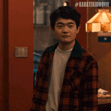 a man in a plaid shirt says thanks in front of a red door