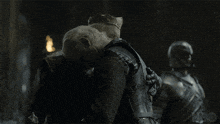 a man with long white hair and a crown talks to another man with a hbo logo in the background