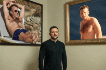 a man stands in front of a painting of a shirtless man laying on a chair