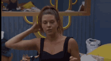 a woman in a black tank top is putting her hair in a bun