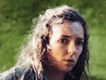 a woman with long curly hair looks at the camera