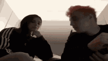 a man and a woman are sitting next to each other in a room . the woman has red hair .