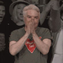 a man wearing a canadian tire shirt is covering his mouth with his hands