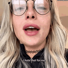 a woman wearing glasses and a choker is saying i hate that for me