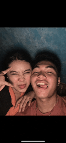 a man and a woman are posing for a picture and the man is sticking his tongue out