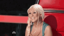 christina aguilera is smiling while sitting in a red chair on the voice .
