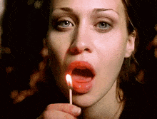 a woman is holding a lit match in her mouth