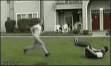 a man is running after another man who is laying on the grass .