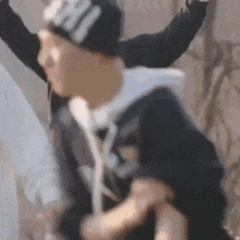 a blurry picture of a man wearing a beanie and a hoodie .