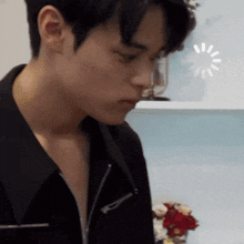 a young man in a black jacket is looking down at something
