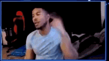 a man in a blue shirt is sitting on a bed in front of a screen .