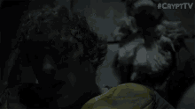 a man in a yellow shirt is laying in a dark room with #crypttv written on the bottom of the screen