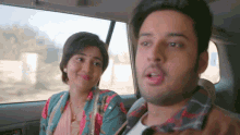 a man and a woman are sitting in a car and the woman is smiling