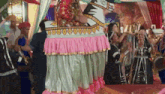 a group of people are dancing in a room with a large statue in the background