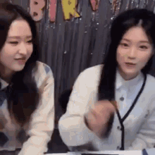 two women are sitting next to each other at a table and laughing .