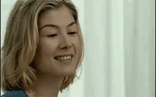 a close up of a woman 's face smiling in front of a white wall .