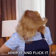 a woman in overalls is whipping her hair and says whip it and flick it