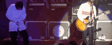 a man playing a guitar on a stage with a marshall amplifier in the background