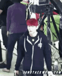 a man with red hair is standing in front of a camera with the website jungtaekwondo.com on the bottom right