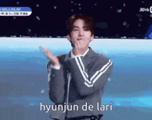 a man in a suit is applauding with the words hyunjun de lari written below him
