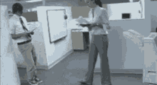a man and a woman standing in a cubicle in an office