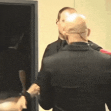 a bald man in a black suit is shaking hands with another man in a black suit