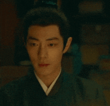 a man in a traditional costume is looking at a candle in a dark room .