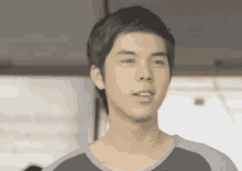 a young man with short hair is wearing a gray and blue shirt .