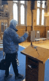 a man in a blue jacket is standing next to a podium