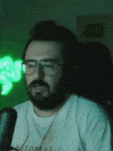 a man with a beard is sitting in front of a microphone .