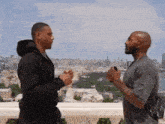 two men are standing on a balcony talking to each other