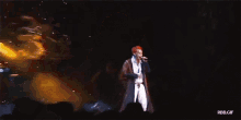 a man with red hair is singing into a microphone while wearing a blue jacket