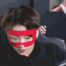 a close up of a person wearing a red mask with devil horns