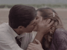 a man and woman are kissing on the beach