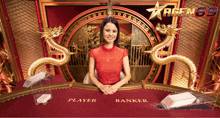 a woman in a red dress sits at a banker table with dragons behind her