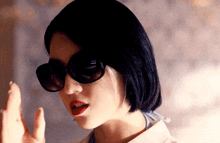 a close up of a woman wearing sunglasses and making a gesture