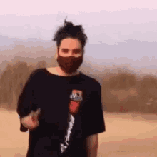 a man wearing a mask and a black t-shirt is standing in the dirt .