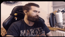 a man with a beard is wearing a black marvel shirt