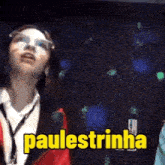 a woman wearing glasses and a lanyard is standing in front of a sign that says paulestrinho