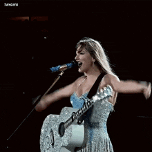 taylor swift is playing a guitar and making a heart shape with her hands .