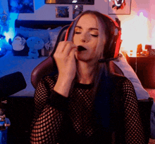 a woman wearing headphones and a fishnet top is sitting in front of a microphone