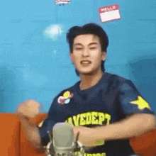 a young man is sitting on a couch in front of a microphone .