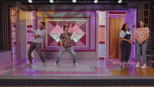 a group of people are dancing in front of a purple wall