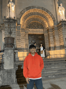 a man in an orange hoodie stands in front of a church