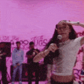 a woman is singing into a microphone while wearing glasses and a crop top .