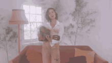 a woman is holding a guitar in front of a red couch