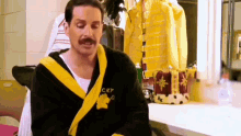 a man with a mustache is wearing a robe and a crown .