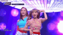 two girls are dancing on a stage in front of a mnet banner .