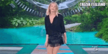 a woman in a black shirt and black skirt is walking down a runway on a stage .